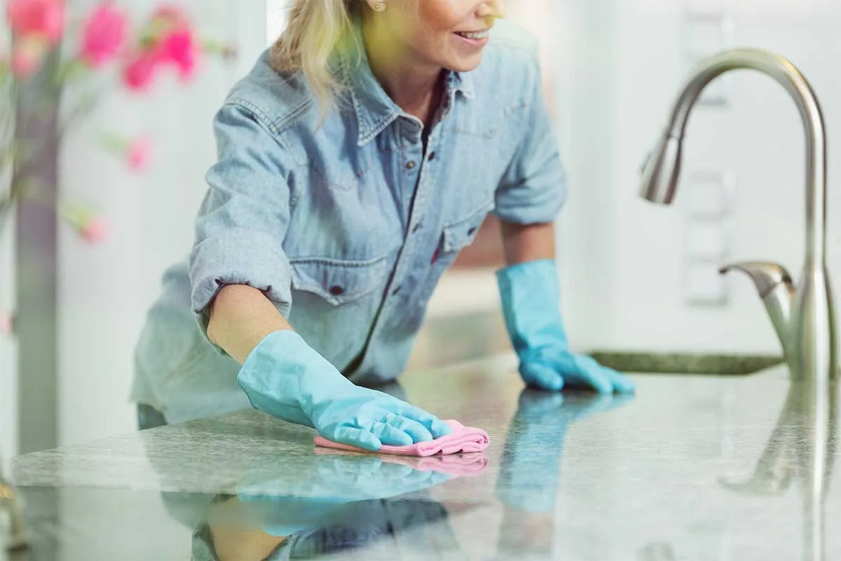 A lady cleaning a granite kitchen worktop